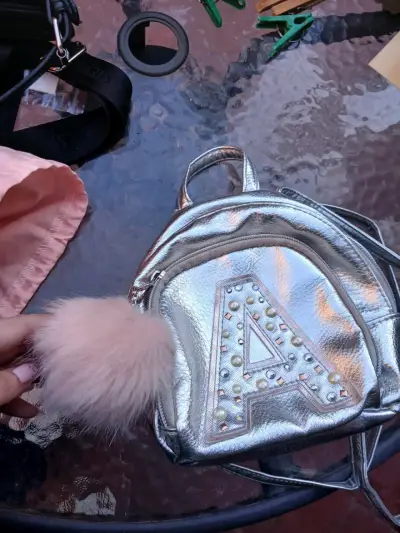 Mochila pequeña plateada con pompón marca Justice - miniatura 1