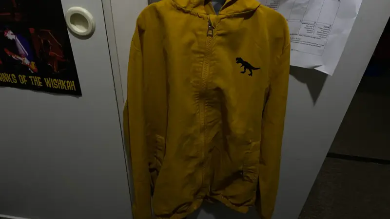 Chaqueta amarilla con capucha y diseño de dinosauo
