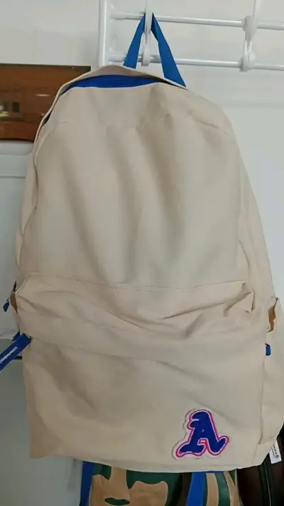 Mochila beige con detalles azules y bolsillo front - miniatura 1