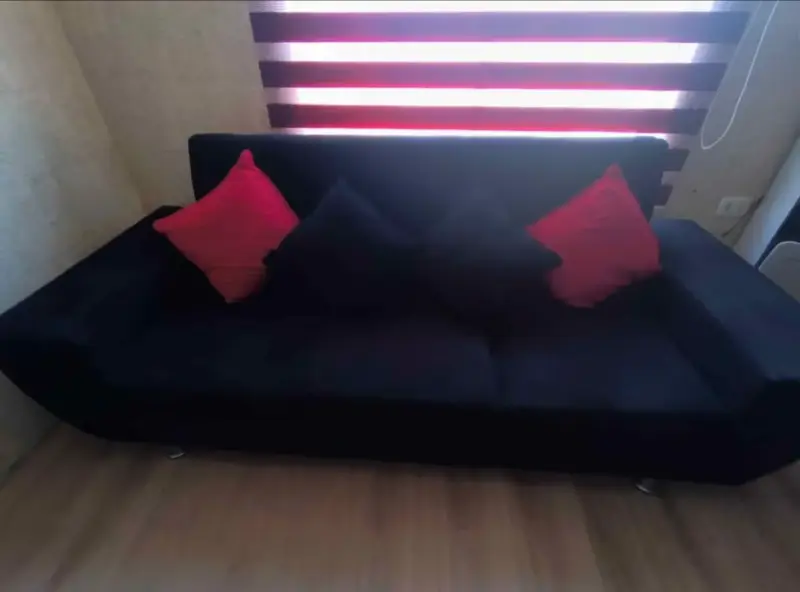 Sofá negro con cojines rojos en buen estado