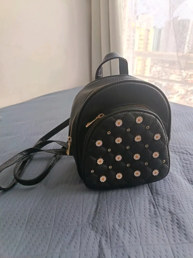 Mochila pequeña negra con flores decorativas