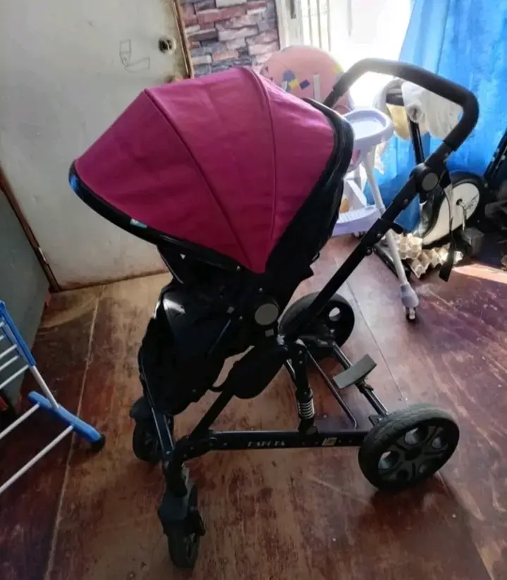 Coche de bebé con capota rosa y estructura negra - 1