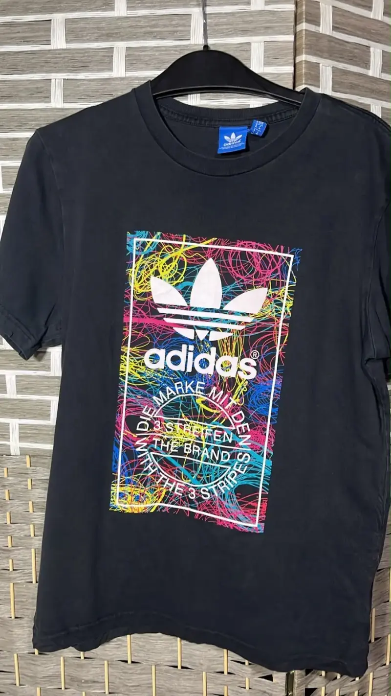 Polera negra Adidas con diseño colorido