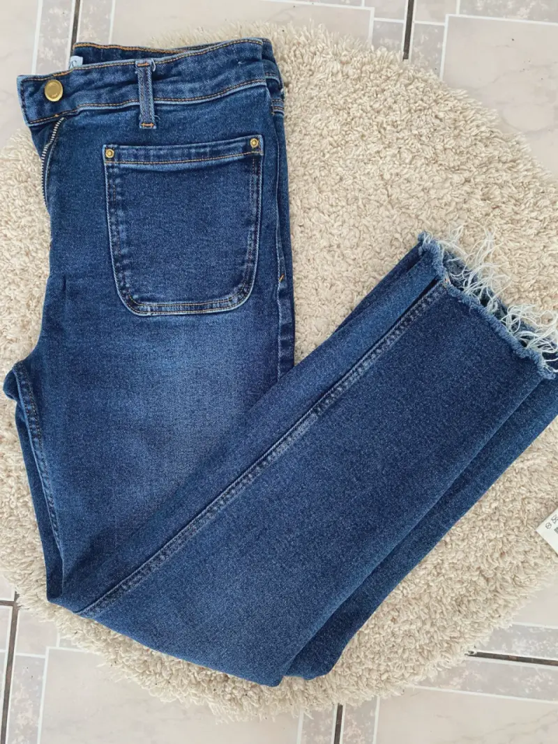 Jeans azul oscuro con dobladillo deshilachado