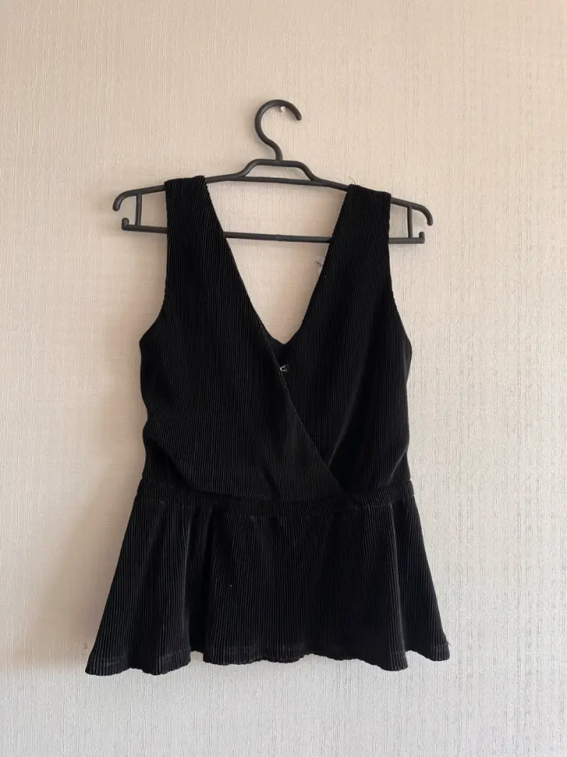 Blusa negra sin mangas con diseño plisado