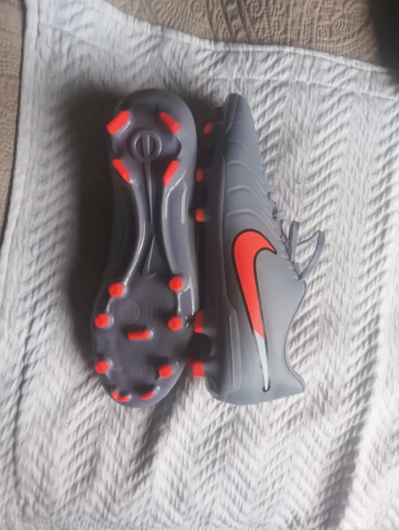 Botines de fútbol Nike grises con detalles naranjas