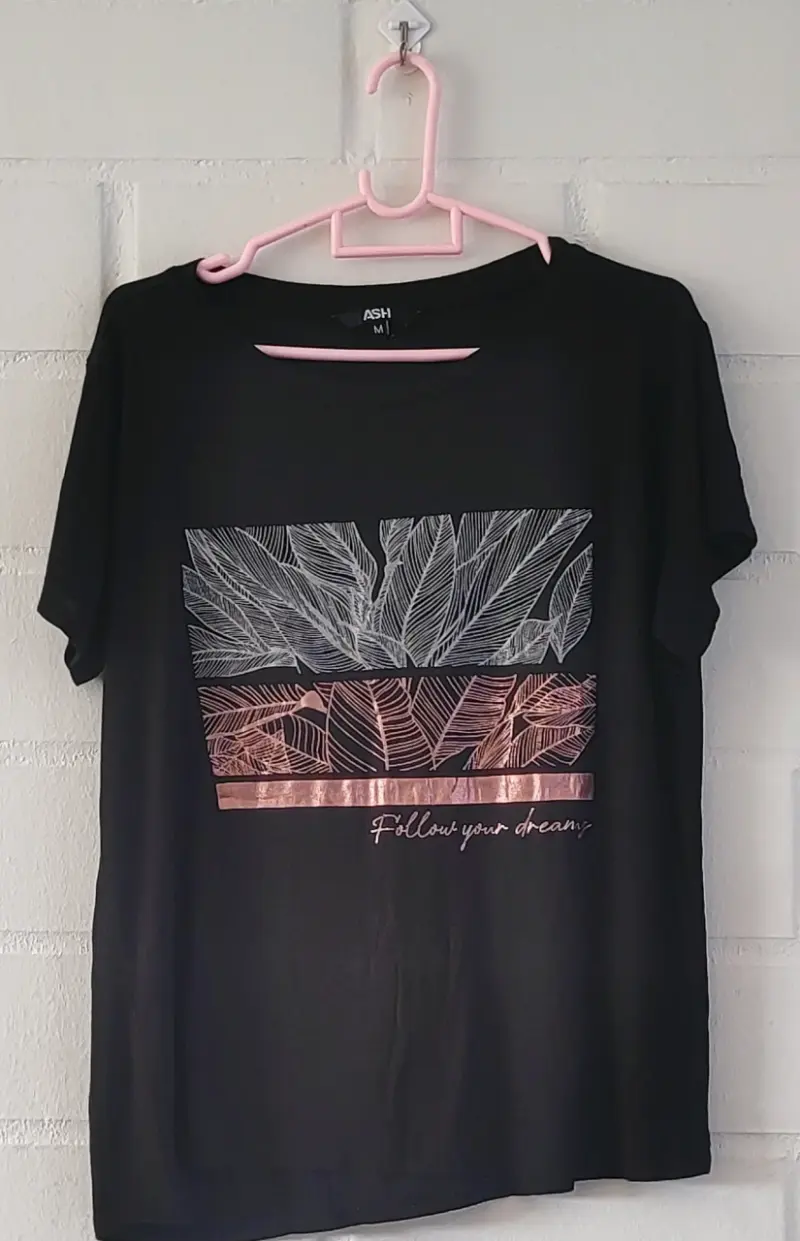 Polera negra con diseño de hojas y frase