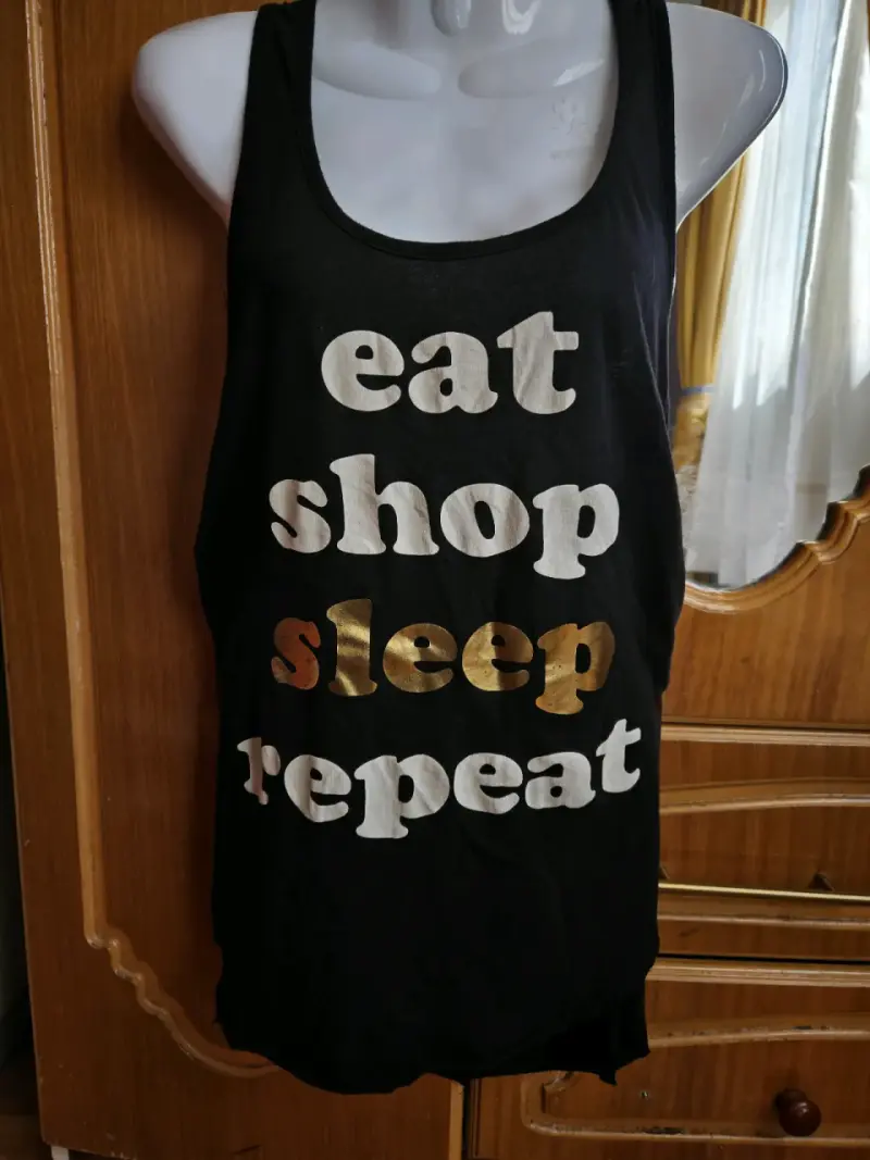 Polera sin mangas negra con texto "Eat Shop Sleep Repeat" - 2