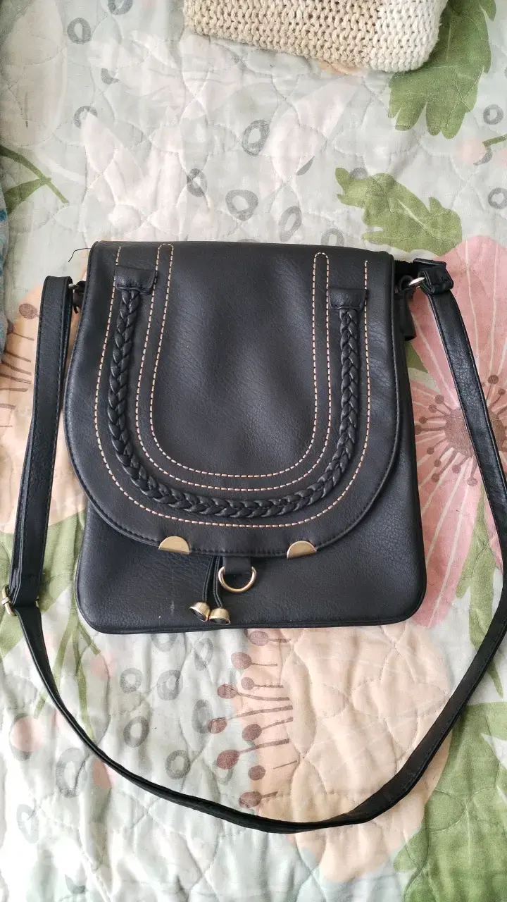 Cartera negra con correa ajustable y detalles trenzados