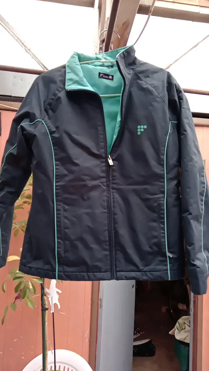 Chaqueta deportiva ploma con detalles verdes agua.
