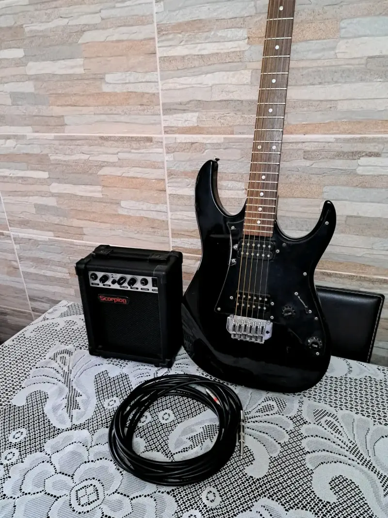 Guitarra eléctrica negra con amplificador y cable - 1
