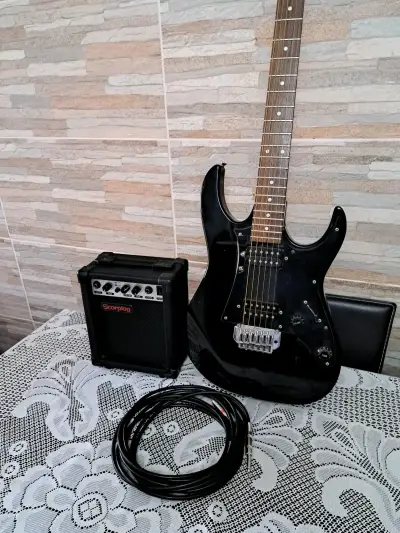 Guitarra eléctrica negra con amplificador y cable - miniatura 1