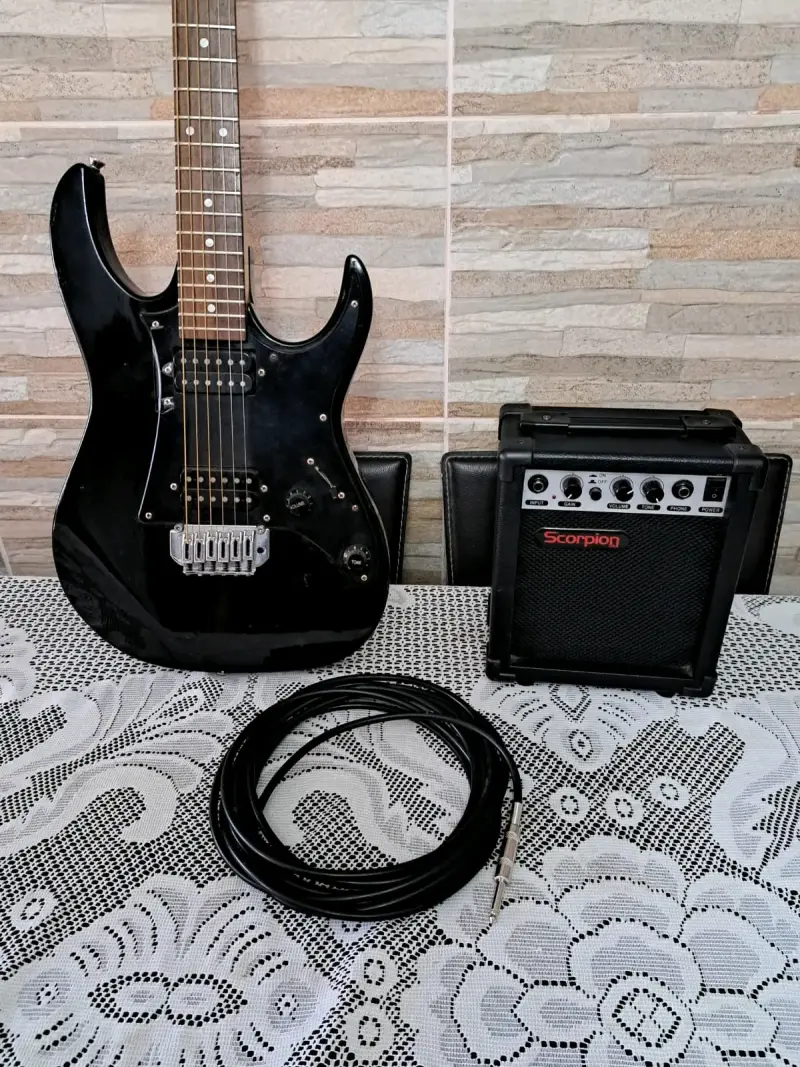 Guitarra eléctrica negra con amplificador y cable - 2