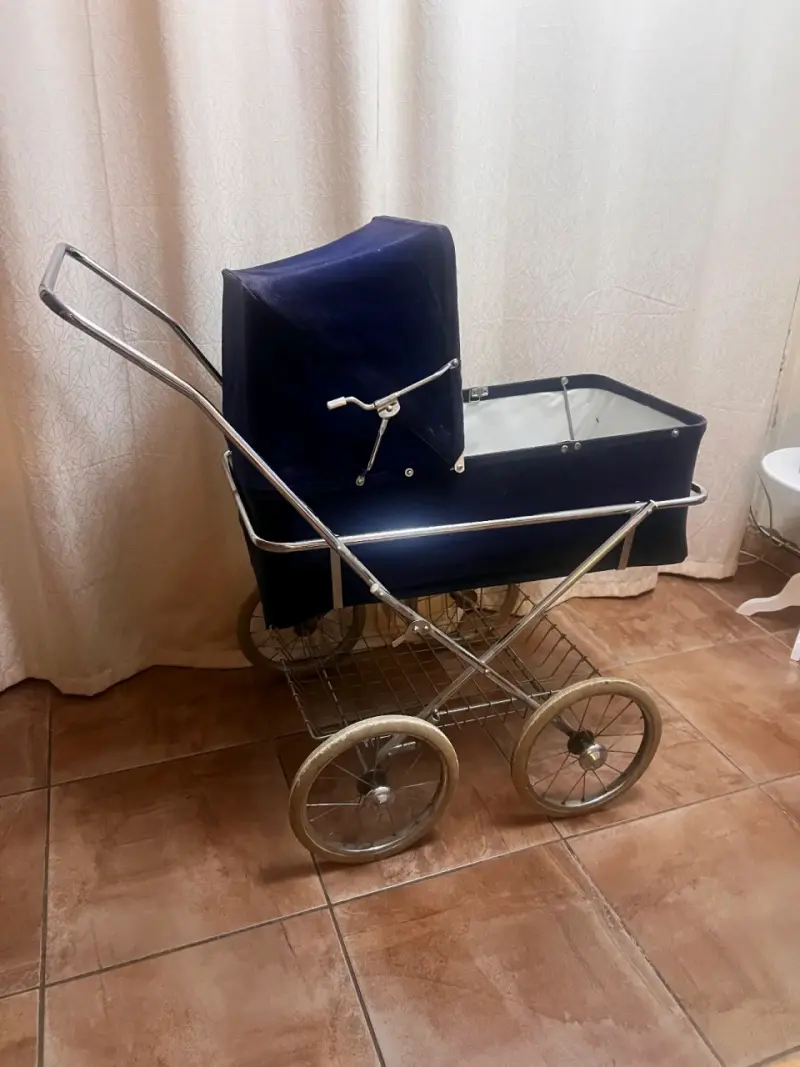 Coche de bebé vintage azul con estructura metálica