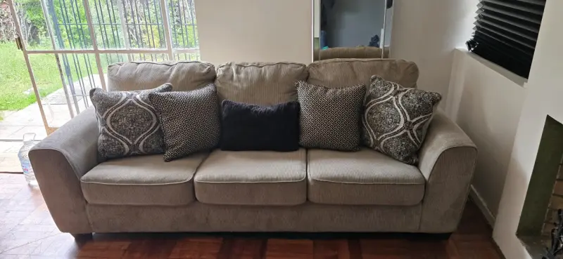 Sofá beige de tres plazas con cojines decorativos - 1