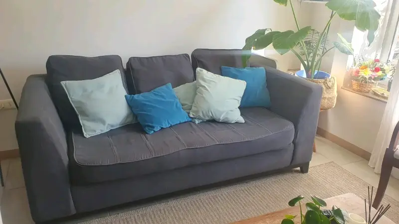Sofá gris de tres plazas con cojines
