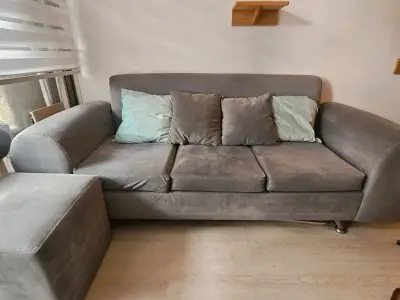 Sofá gris con cojines y puff - miniatura 1