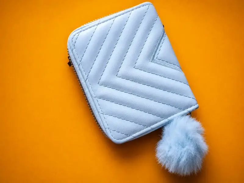 Monedero azul con diseño acolchado y pompón