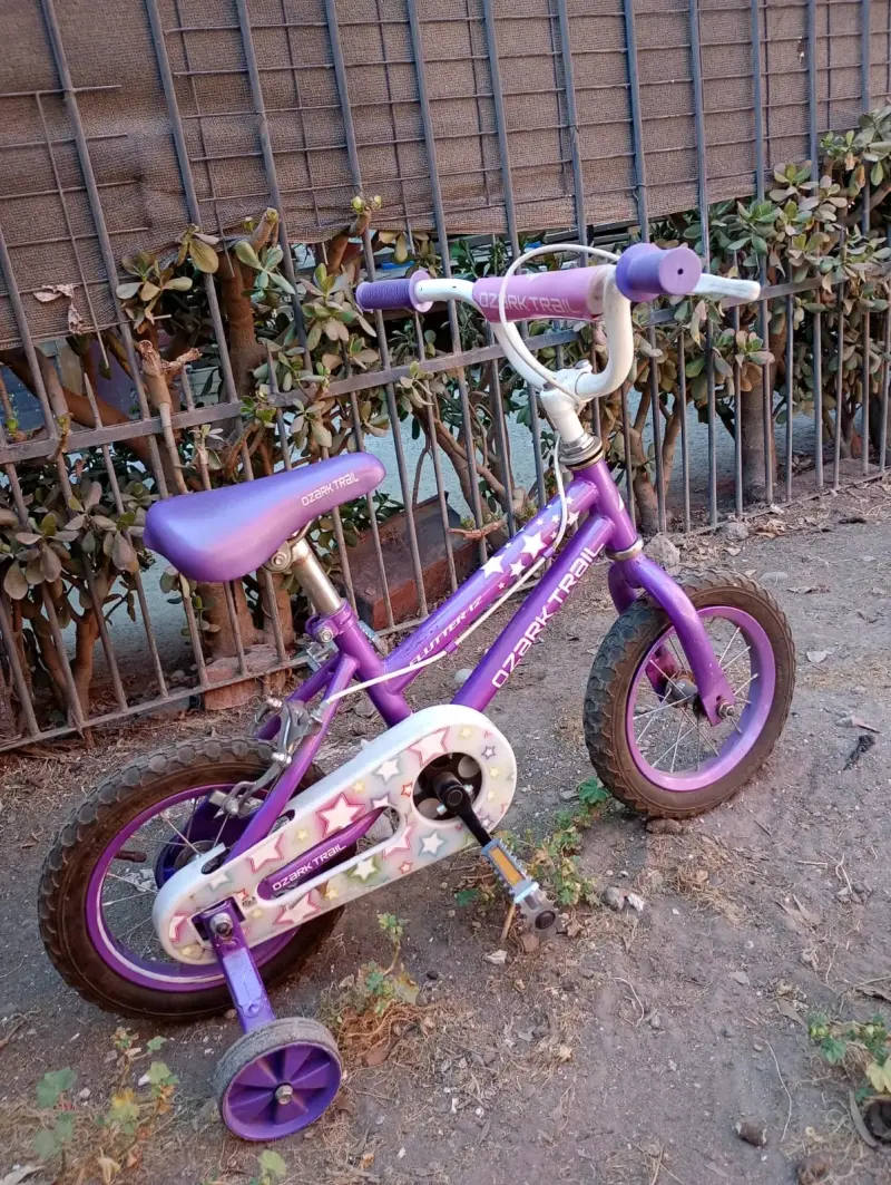 Bicicleta infantil morada con ruedas de apoyo