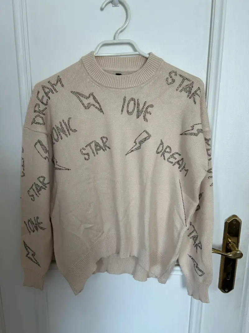 Suéter beige con diseño de palabras y cristales