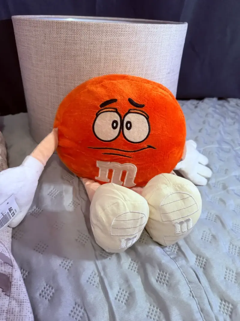 Peluche naranja M&M's con expresión divertida