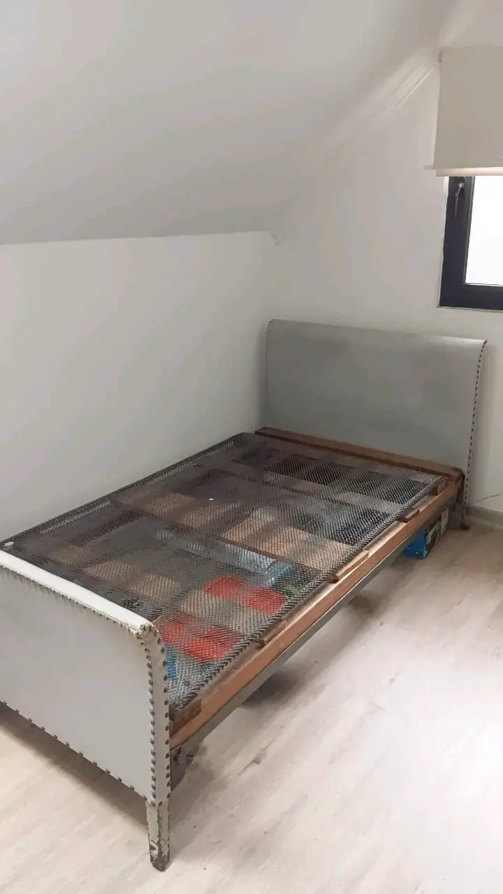 Cama individual con estructura metálica y respaldo acolchado - 1