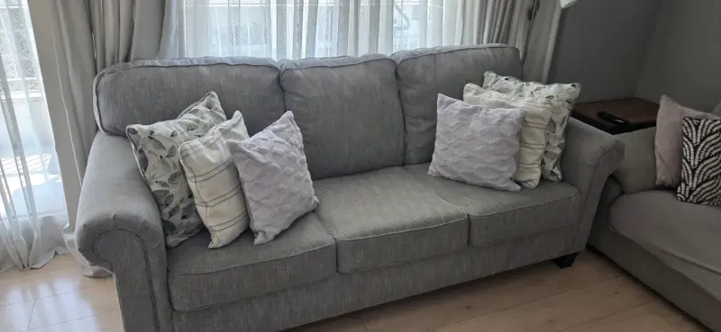 Sofá gris de tres plazas con cojines decorativos