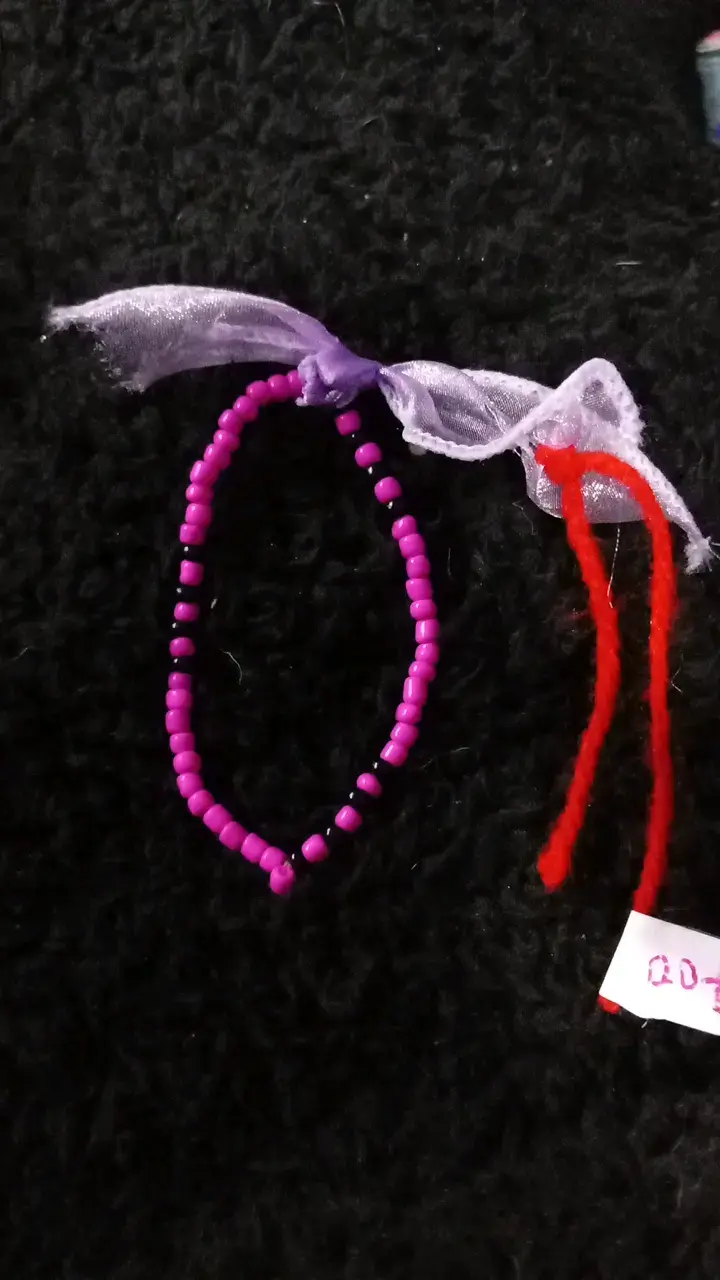 Pulsera de cuentas moradas con lazo decorativo
